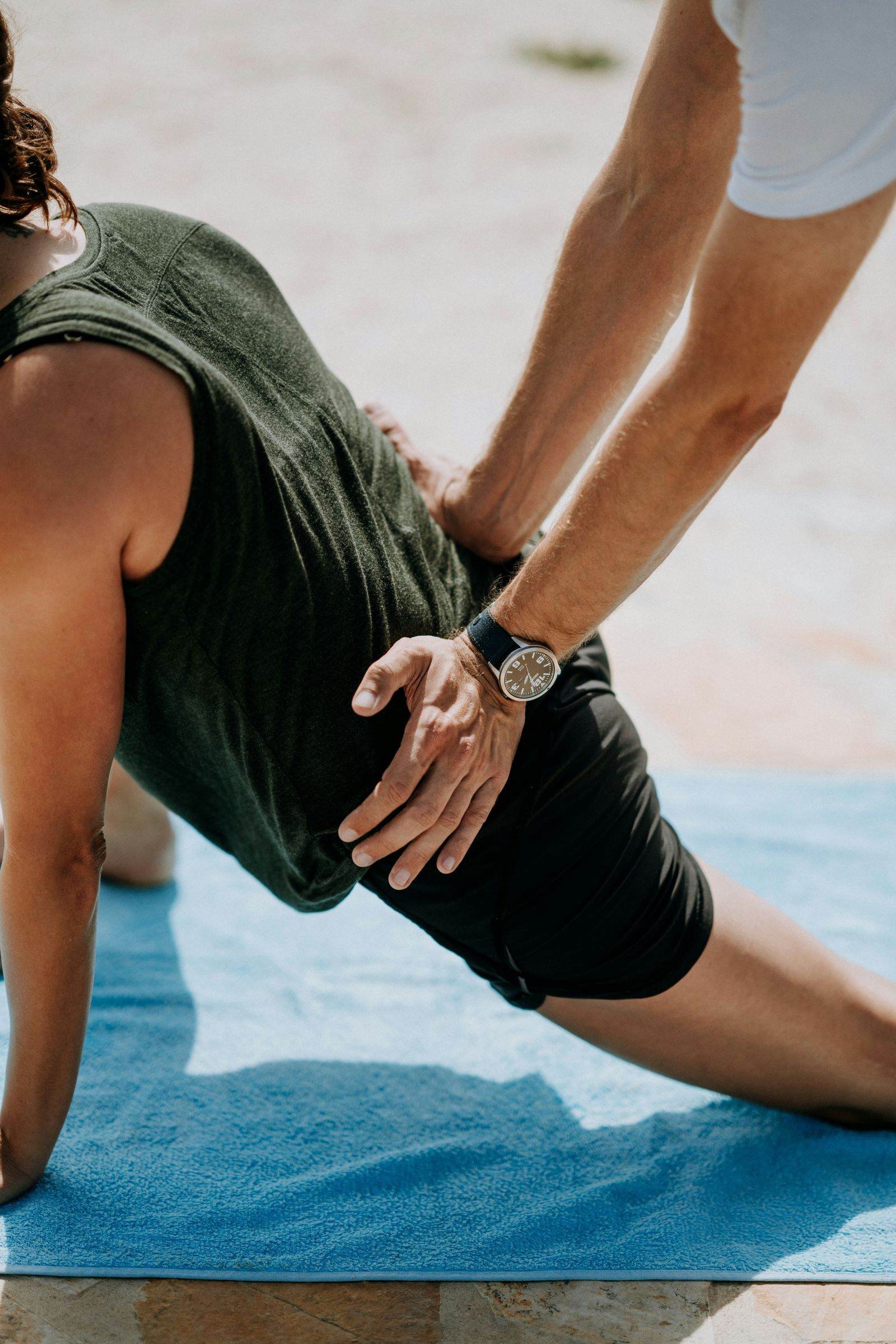 Hands guiding a kneeling hip stretch on an exercise mat